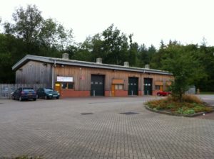 An outside view of the units. The building is surrounded by a large parking area.