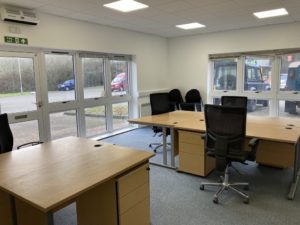 An inside view of the office space. There are large desks with space for five people. There are large windows on both walls.