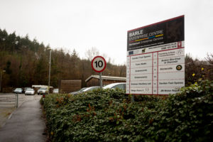 A view from the entrance of the estate looking in. There is a large sign listing the units and their occupants.