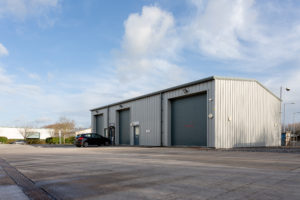 External view of a Somerset Enterprise Centre Highbridge unit showing the 3 large roller doors on the side of the building. There is ample space for large vehicles to unload.