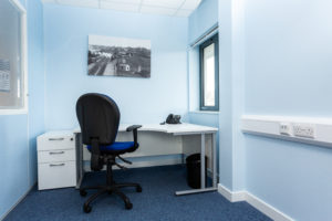 A small office space for one person with a single desk and drawers and a small window.