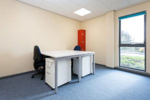 Wells small office space. There are two desks facing eachother and a large floor to ceiling window.