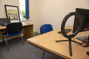 Inside view of a small Williton enterprise office. There are two desks with computers and a ring light.