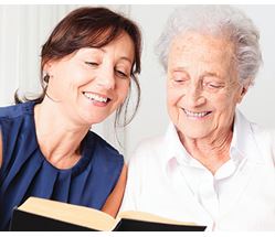 Younger woman helping older woman with a book
