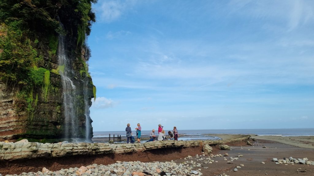People having a picnic under a waterfall on a beach