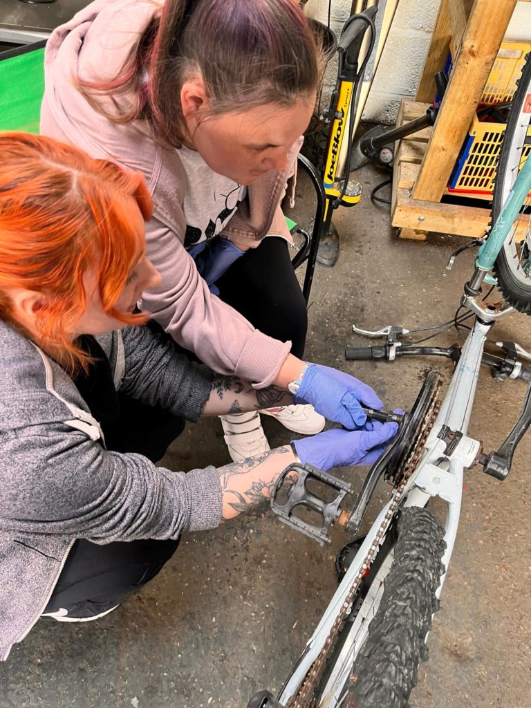 Beth (left) and Annabel, from the Hub, a special needs daycare centre in Yeovil, learn bike repair techniques on a day visit to Prodigal Bikes, Crewkerne.