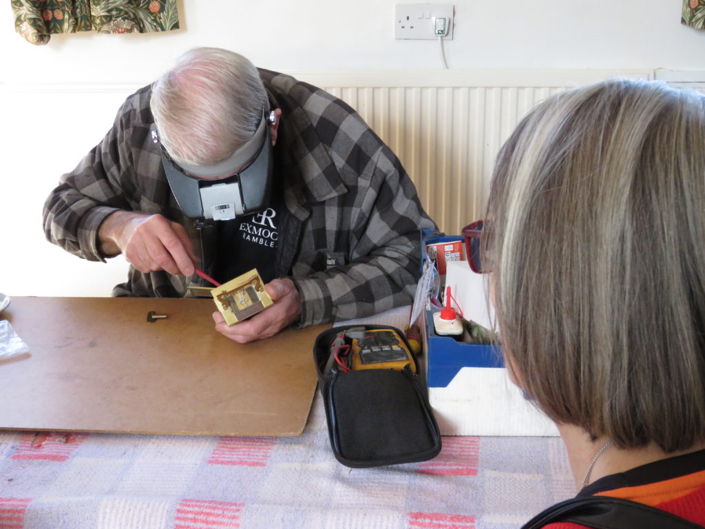 A volunteer repairer fixes a clock