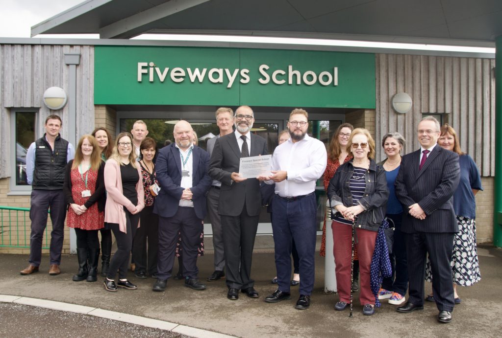 Headteacher, Swavek Nowakiewicz and Lord Lieutenant of Somerset, Mohammed Saddiq, hold the new plaque outside the school. Joined by: Cllr Bill Revans – Lead Member for Somerset Council, Duncan Sharkey – Chief Executive of Somerset Council, Claire Winter – Director for Children, Families and Education at Somerset Council, Claire Merchant Jones – Head of Special Educational Needs and Disabilities (SEND) at Somerset Council, Heather Good – Head of Education Leadership at Somerset Council, Phil Curd – Head of Education Places at Somerset Council, Marie Palmer – Education Relationship Manager at Somerset Council, James Holgate - Assistant Headteacher, Sam Ensor - Deputy Headteacher, Naomi Austin - Assistant Headteacher, Fiona Bunkin - Business Manager, Kirstie Kerr - SENCo, Tracey Richards - Deputy Chair of Governors holding up a new plaque outside Fiveways school.