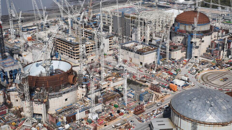 Aerial view of the construction activity at Hinkley Point C, including the three reactors and a multitude of cranes.