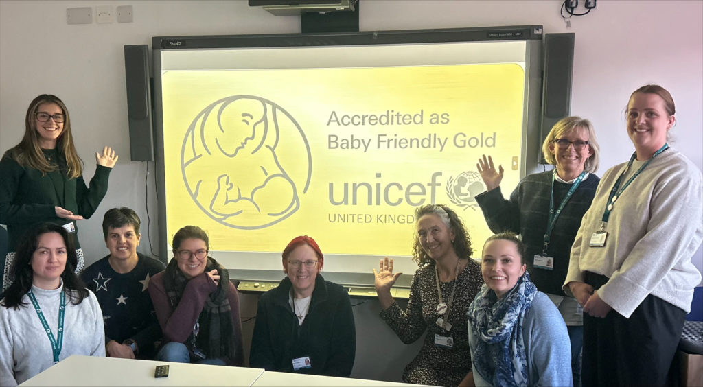 Photo of Somerset Health Visitors, Left to Right: Standing left as look at picture: Bryony Shanley Crouching: Kerry Moody, Lucinda Rivers, Carly Delbridge, Kate Baigent, Amber Austin (Infant Feeding Lead), Chloe Hill, Standing right side of picture as look at it: Anita Granum, Gemma Cooper