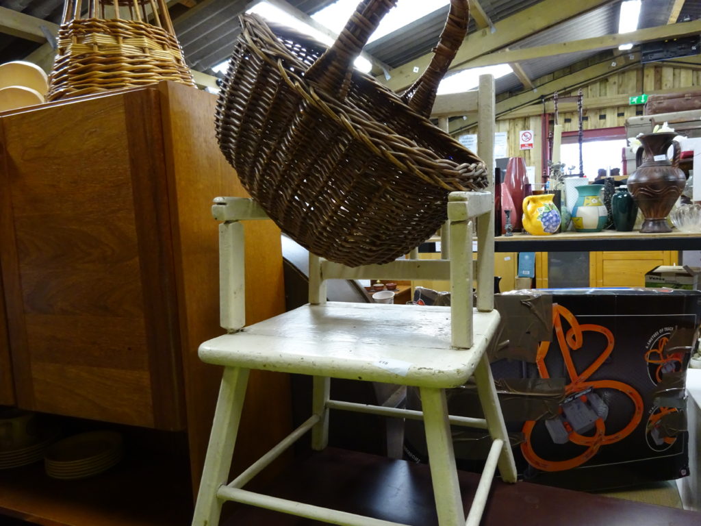 Interior view of Taunton Reuse Shop with used items on display, including furniture an a straw basket.